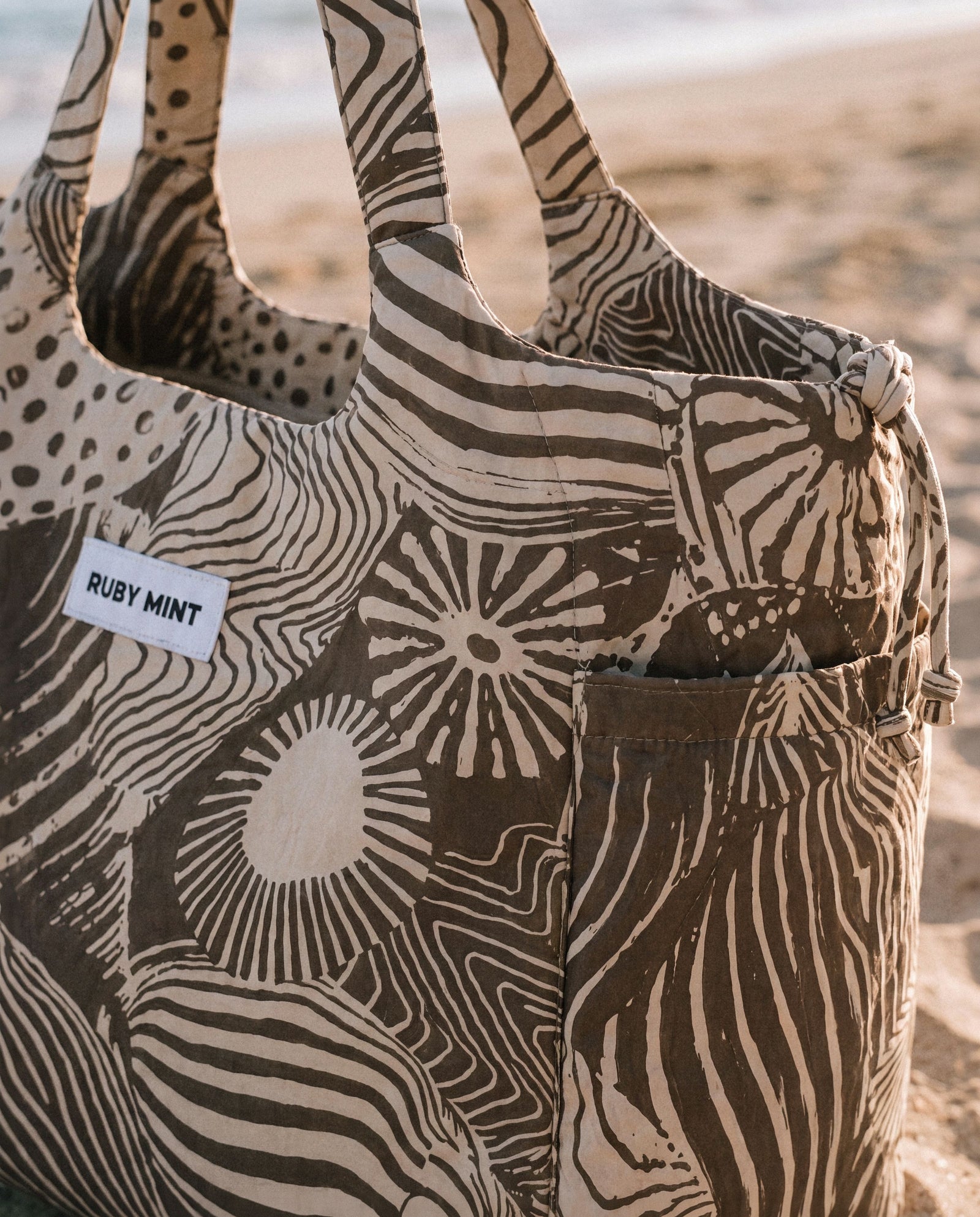 Close detail of the Everyday Tote in a brown abstract print with the Ruby Mint woven label