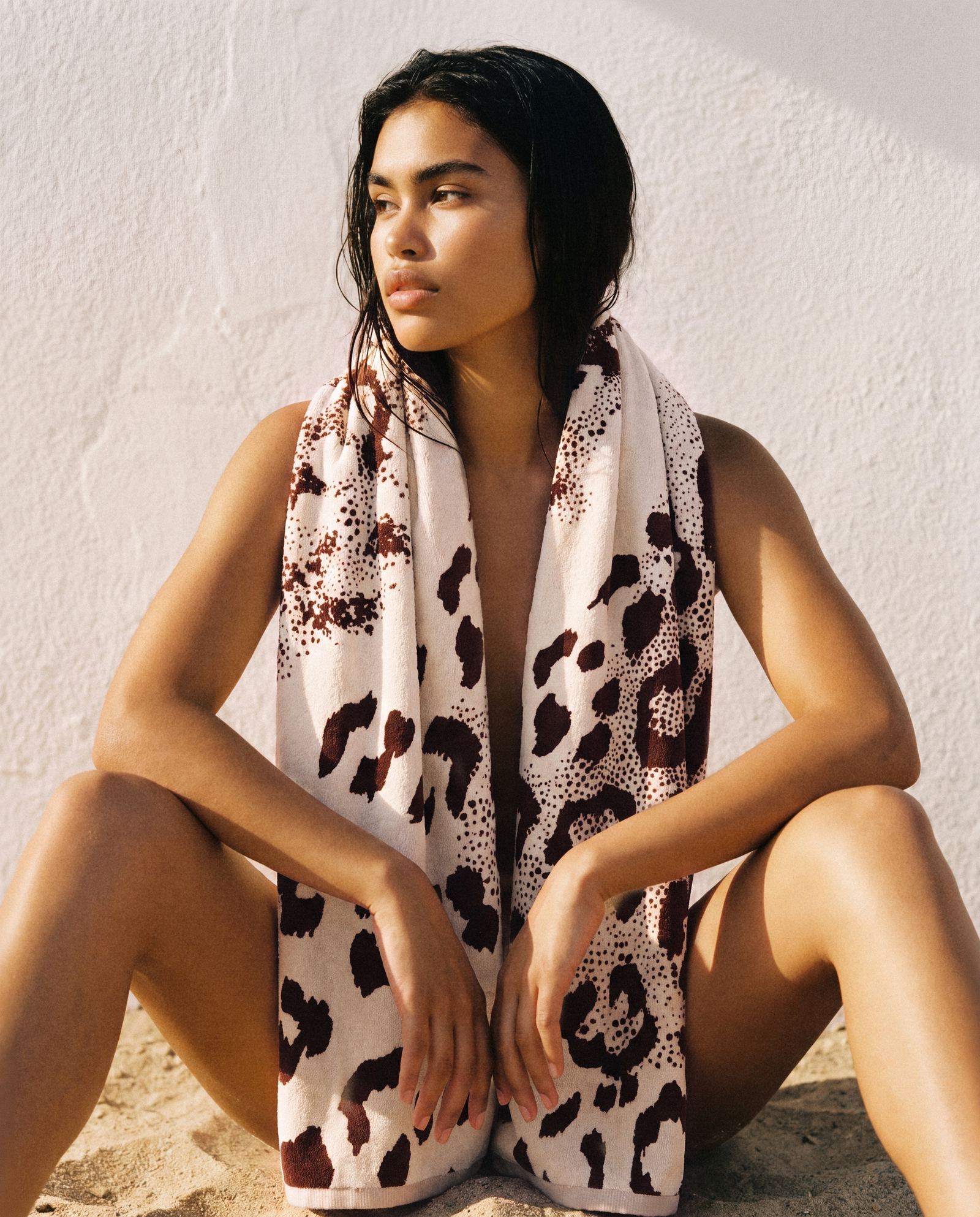 Model seated with a Tigerlily-print pareo against a white plaster wall